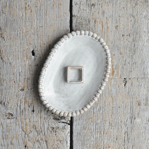 A snow-white ceramic beaded oval dish with a small, raised stoneware soap rest. Nom Living