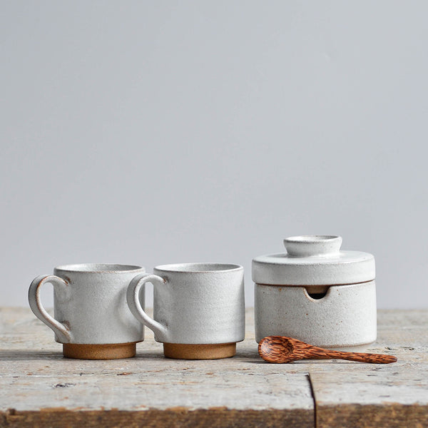 Handmade snow white ceramic coffee set featuring two stackable stoneware espresso cups and a matching lidded sugar bowl with a spoon. Nom Living