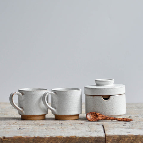 Handmade snow white ceramic coffee set featuring two stackable stoneware espresso cups and a matching lidded sugar bowl with a spoon. Nom Living