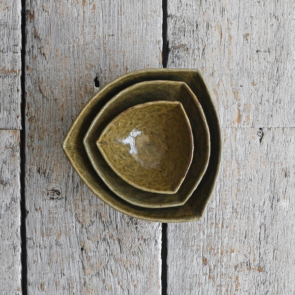 Three-piece nesting set of deep green stoneware bowls in an organic triangular shape with a hand-moulded dimpled texture