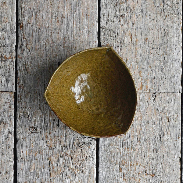Triangular green ceramic snack bowl with a hand-moulded organic shape and irregular rim, designed as a minimalist serving piece for chips, crackers, and party snacks