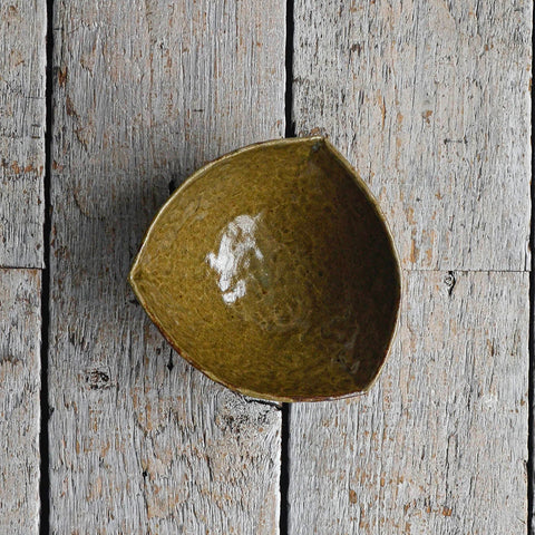 Triangular green ceramic snack bowl with a hand-moulded organic shape and irregular rim, designed as a minimalist serving piece for chips, crackers, and party snacks