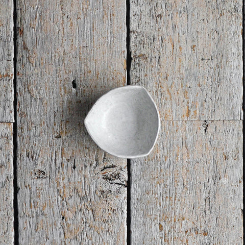 Mini hand-shaped stoneware bowl in deep green, featuring an organic triangular silhouette for salt, oil, and individual condiments. Placed on a wood table